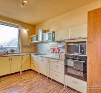 A kitchen in a family house with a wooden decor floor, light kitchen cabinets, built-in appliances.