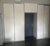 A two-room apartment with a dark floor and built-in wardrobes near the entrance door.