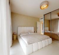 Bedroom in a 4-room apartment, light walls, mirrored wardrobe, large windows with curtains.