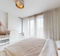 A bedroom in a 4-room apartment with a crib, a bed, and curtains on the windows.