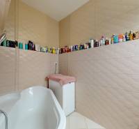 A bathroom with a shower, bathtub, and various products in a 4-room apartment.