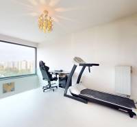 Home office with a desk, treadmill, and shelves in a 4-room apartment.