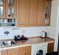 Kitchen unit with wood decor, built-in oven and washing machine in a studio apartment.