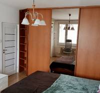 Bedroom with a mirrored wardrobe, bed, and furnishings in a studio apartment.