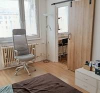 Interior of a 1-room apartment with a wooden decor floor, an armchair, and sliding doors.