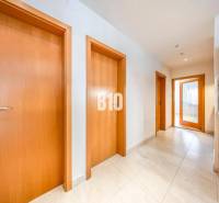 A hallway in a 3-room apartment with multiple doors and light-colored tiles.