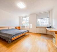 A bedroom in a 3-room apartment with a wooden decor floor and a large bed.