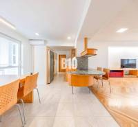 A bright kitchen of a 3-room apartment with a wooden decor floor and a dining table.