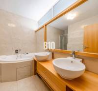 A bathroom with a corner bathtub and two sinks in a 3-room apartment with a wooden decor.