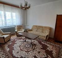 Living room in a family house with a carpet, sofa, and armchairs, large window.