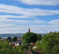 A view of the roofs and greenery of Hronské Kosihy with a view of family houses and mountains.