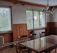 Dining in a family house with wooden paneling, table, and chairs.