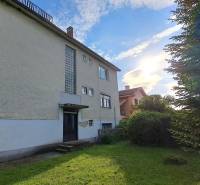 A family house in Hronské Kosihy with a garden, trees, and a clear sky.