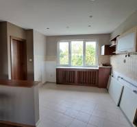 A kitchen in a family house with light walls and wooden cabinets.