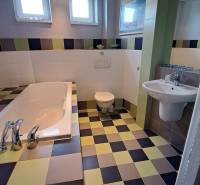 A bathroom in a family house with a tiled floor and a bathtub, spacious and bright.