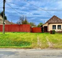 A family house in Budmerice with a red fence and a front garden behind the power lines.