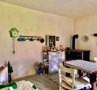 A dining room in a family house with a stove, a table, and decorative clocks on the wall.
