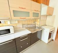 A kitchen in a 2-room apartment with a kitchenette, stove, microwave, and storage space.