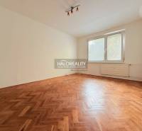 A room in a 2-bedroom apartment with a wood-decor floor and a large window.