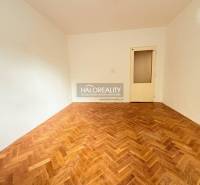 A room in a 2-room apartment with a wood-decorated floor and light-colored walls.