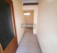 A narrow hallway with tiles and wooden doors in an office.