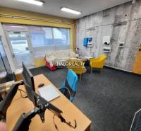 Office with carpet, computers, sofa, and colorful chairs.