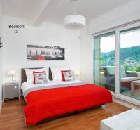 Bedroom in a villa with wood-patterned flooring, a bed, and a balcony with a view.