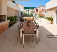 A villa in the town of Bol with an outdoor terrace, table, and grill surrounded by plants.