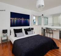 Bedroom in a villa with wood-decor flooring, a mirror, and a stylish bed.