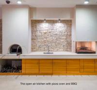 A villa with an outdoor kitchen, stone wall, and pizza oven.