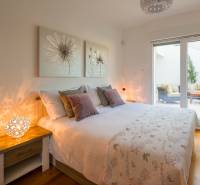 Bedroom in a villa with wood-patterned flooring, delicate paintings, and large windows.