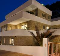 The exterior of a villa in the town of Bol with bright terraces and stone walls at dusk.