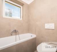 Bathroom with a bathtub and a window in a 2-room apartment, tiles with a beige decor.