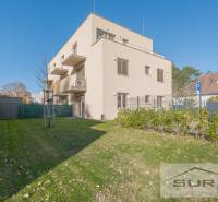 A building with two floors, green grass, and blue sky on Železničná Street in Bratislava.