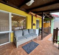The veranda of the cottage at Trnkova 213, Bžany, with a gray sofa and tiles.