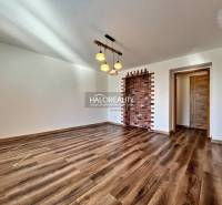 Living room in a three-room apartment with a wooden decor floor and a brick wall.