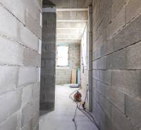 A hallway in an under-construction family house with a view of concrete walls.