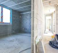 Interior of an unfinished family house with concrete walls and large windows.