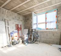 Unfinished interior of a family house with brick walls and construction materials.