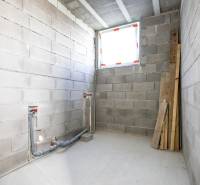 Unfurnished room with concrete walls and floor, ready for installations in a family house.