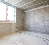 Interior with unfinished walls, electrical wiring installation, and a window in a family house.
