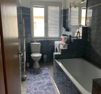 A bathroom with blue tiles and a bathtub in a 2-room apartment.