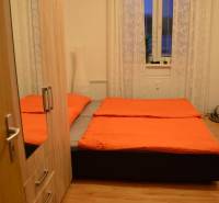 A bedroom in a 2-room apartment with a bed, wardrobe, and wooden decor flooring.