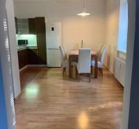 Dining area with wood-patterned flooring in a 2-room apartment, table and four chairs.