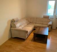 Living room in a two-room apartment with a corner sofa and a floor with a wooden decor.