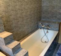 A bathroom with a cast iron bathtub and steps, typical for a 2-room apartment.