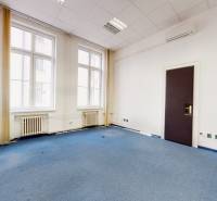 The interior of an office with a blue carpet, white walls, and large windows.