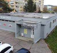 A commercial building in Rimavská Sobota, surrounded by apartment blocks and parked cars.