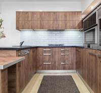 A kitchen in a 2-room apartment with wooden cabinets, white tiles, and a floor with a wooden design.