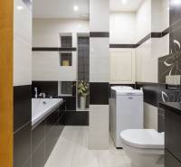 Bathroom in a 2-room apartment with a bathtub, washing machine, toilet, and decorative tiles.